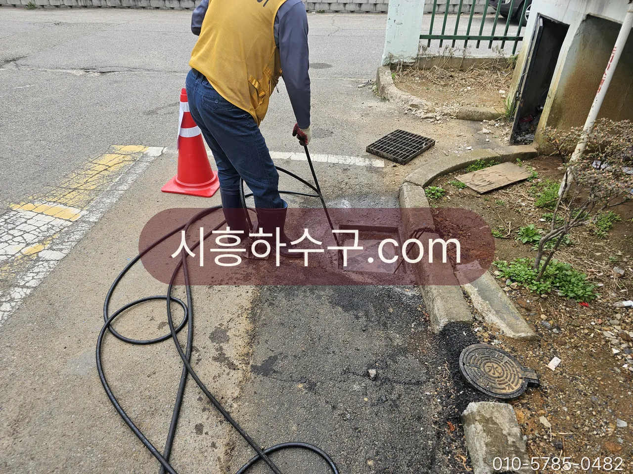 건물 밖 배수구를 열고 고압세척 호스로 뚫는 작업