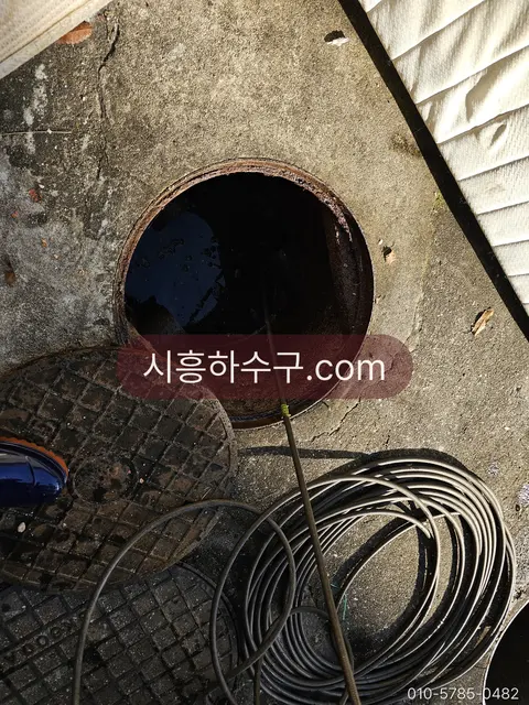 긴 옥외 관로를 따라 릴을 풀어 맨홀 사이 구간을 세척하는 현장